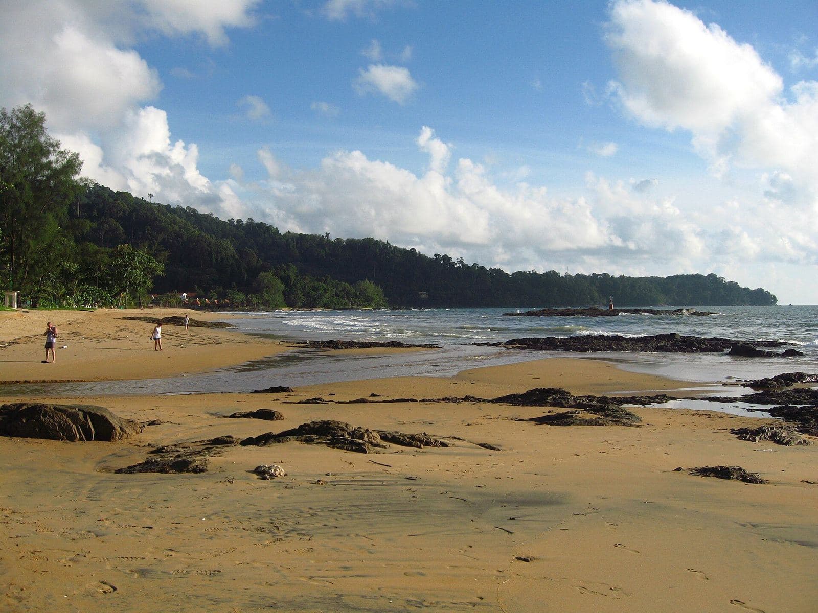 Nang Thong Beach at low tide, rocks in the foreground and the headland beyond
